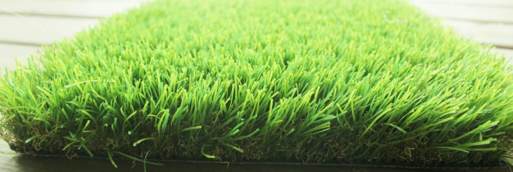 Close-up texture of dense, bright green synthetic artificial grass turf.