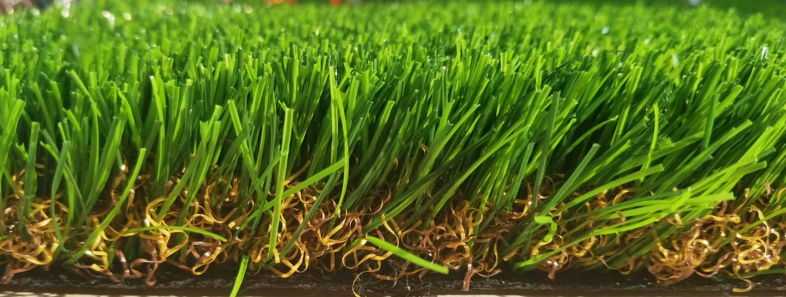 High-quality artificial grass turf texture, featuring green blades and brown curly thatch.